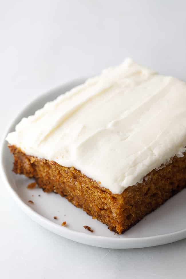 Single square of homemade pumpkin spice cake with thick cream cheese frosting