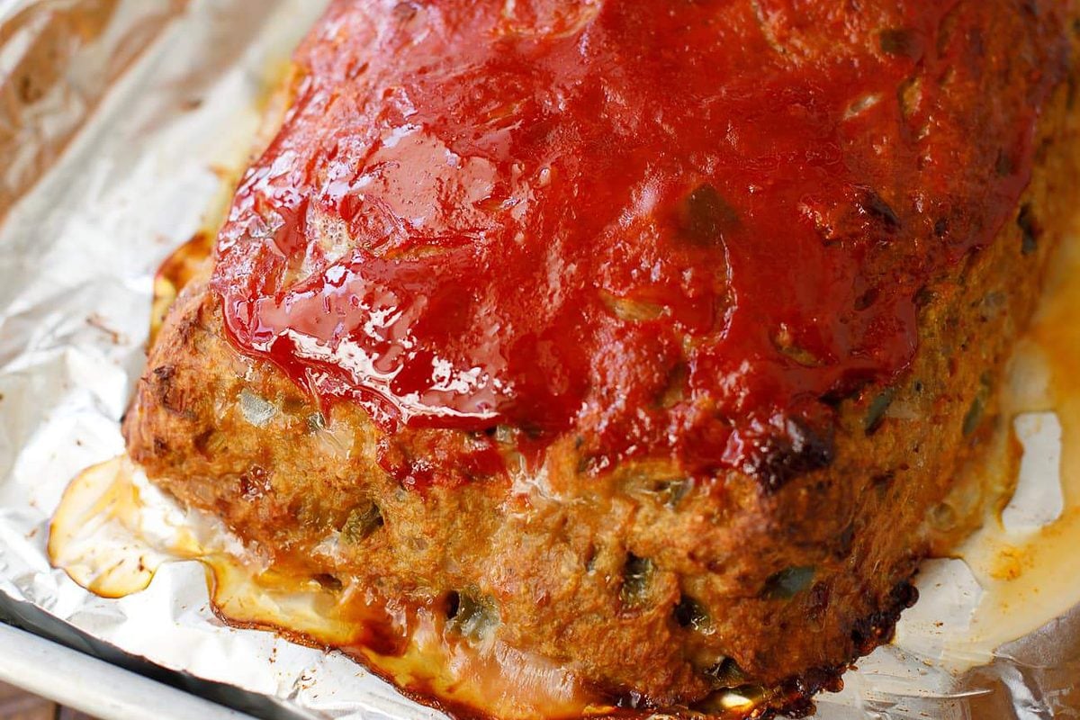 Whole turkey meatloaf with a shiny ketchup glaze on a foil-lined baking pan