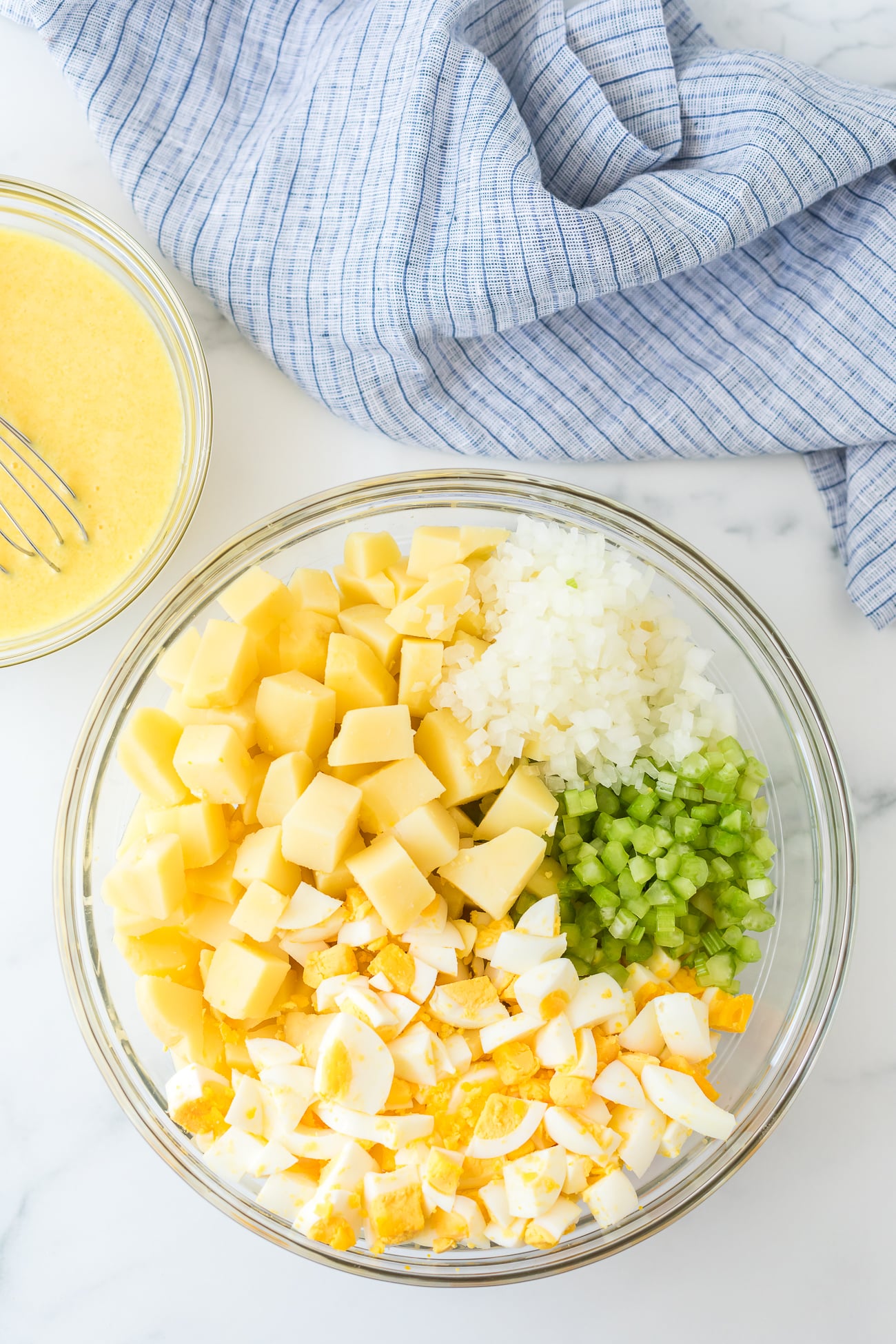 Old-fashioned potato salad with eggs and celery in a white mixing bowl