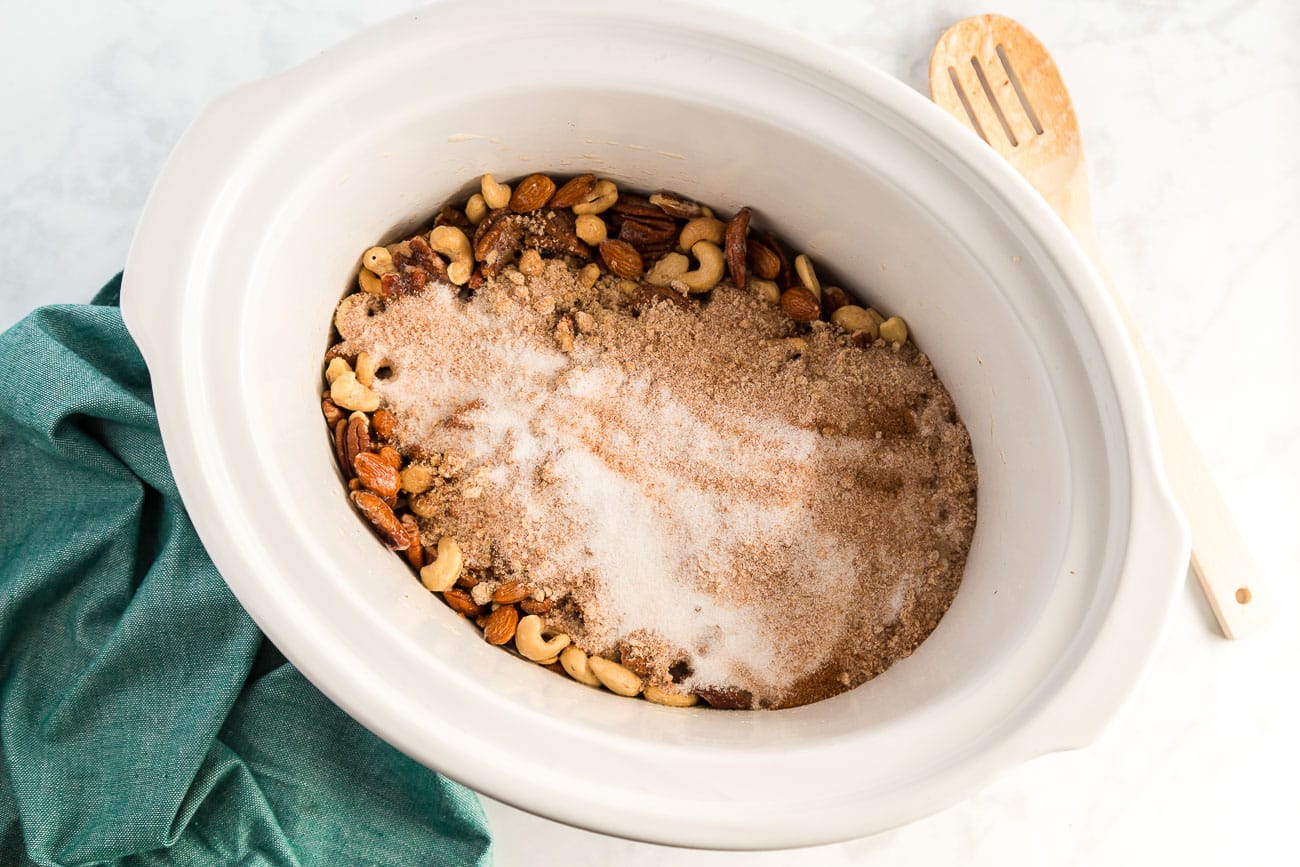 sprinkling brown sugar and white sugar mixture over mixed nuts