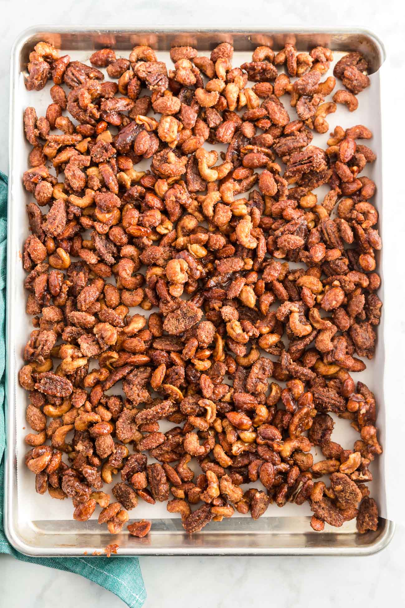 crock pot candied nuts cooling on parchment paper