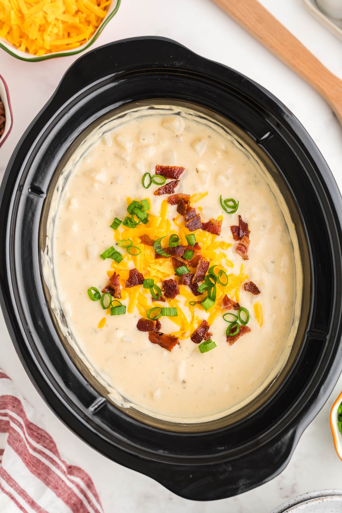 Finished Crock Pot potato soup made with frozen hash browns, topped with bacon, cheddar and green onions