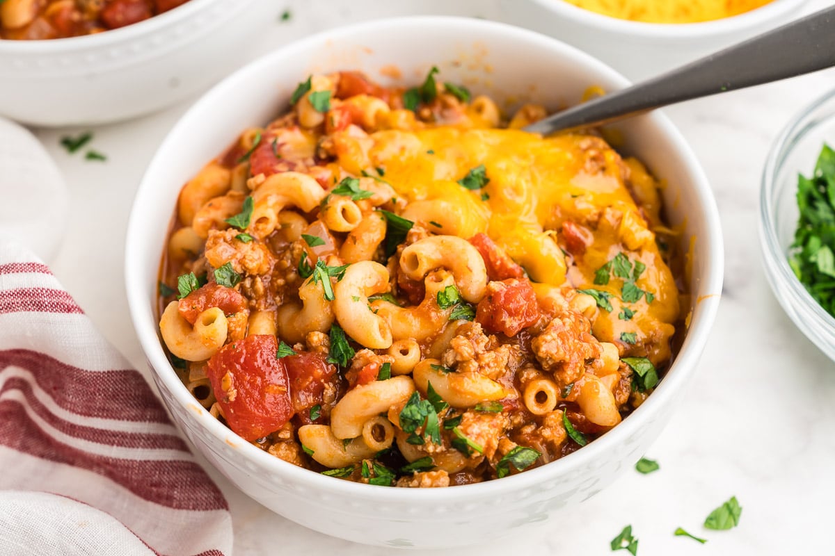Bowl of ground turkey goulash with cheddar cheese, ready to serve