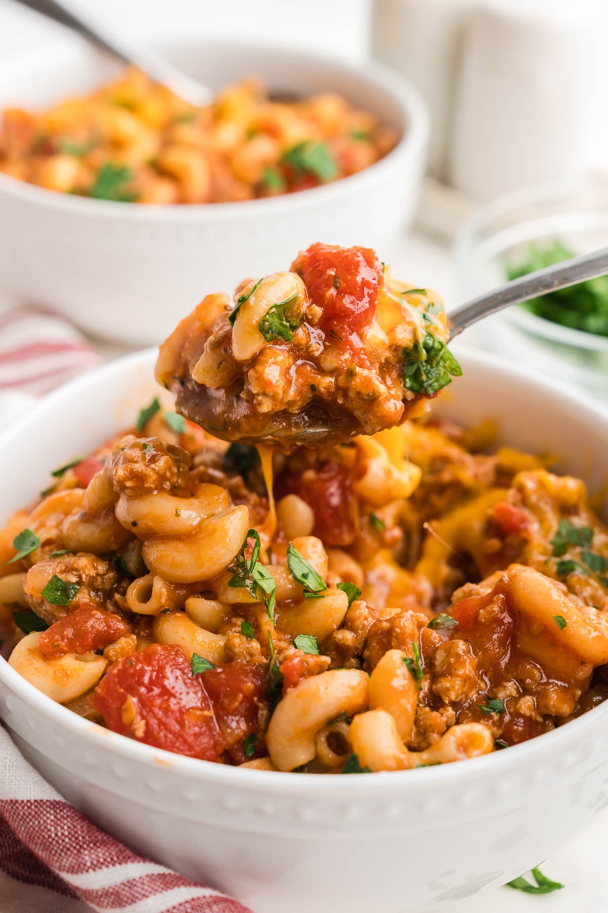 Close-up of a spoonful of cheesy elbow macaroni with diced tomatoes