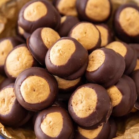 Homemade buckeye balls piled in a parchment-lined bowl.