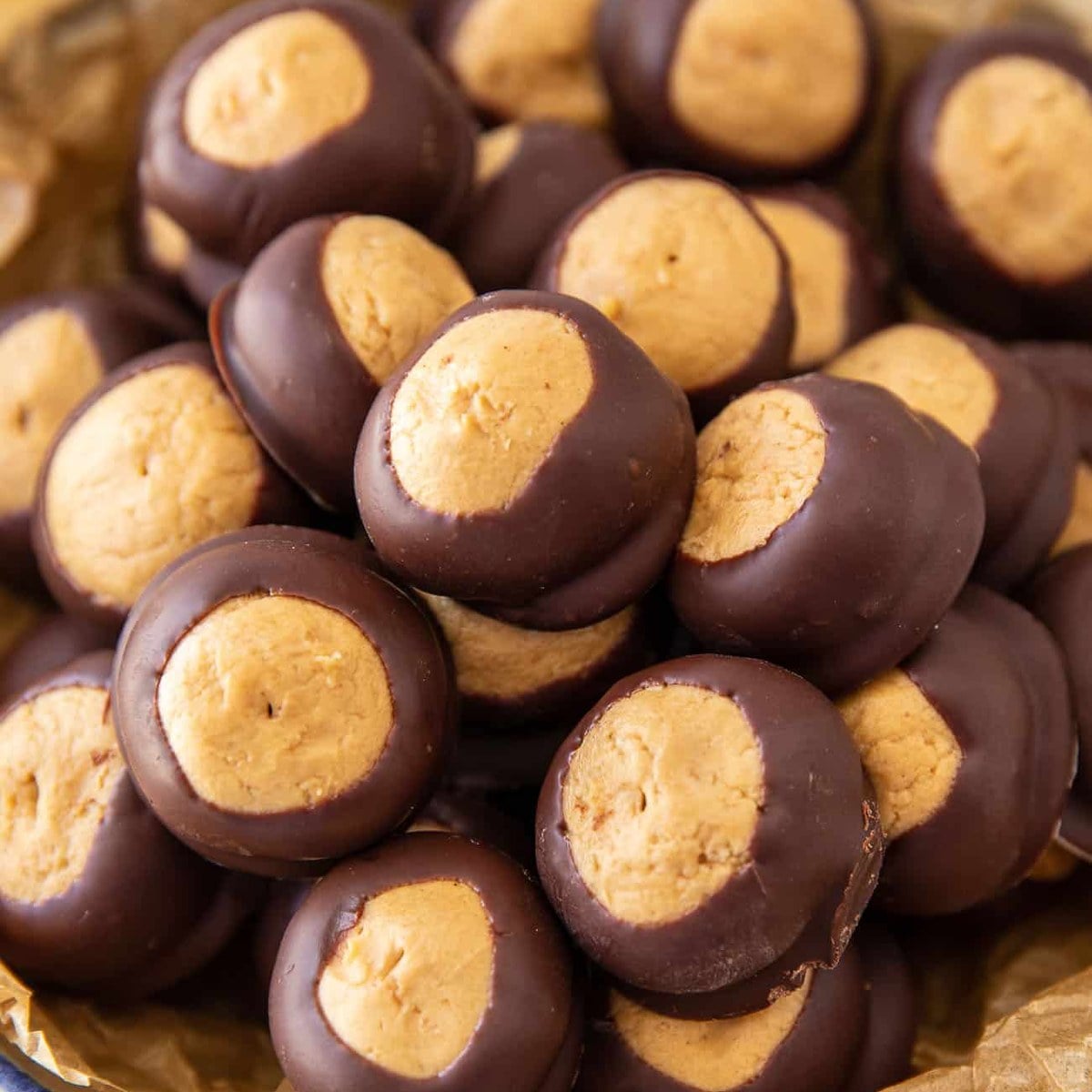 Homemade buckeye balls piled in a parchment-lined bowl.