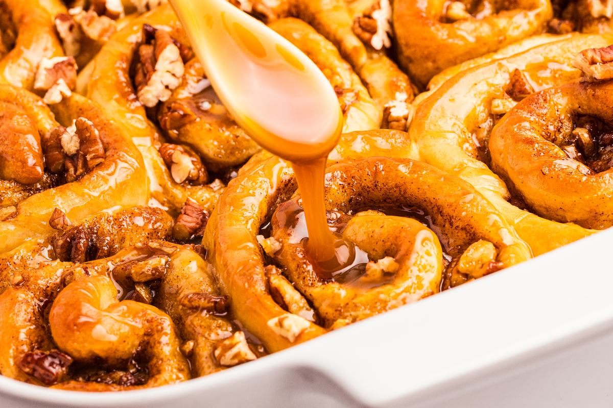 Spoon drizzling a warm, golden sauce over a baking dish fresh from the oven.