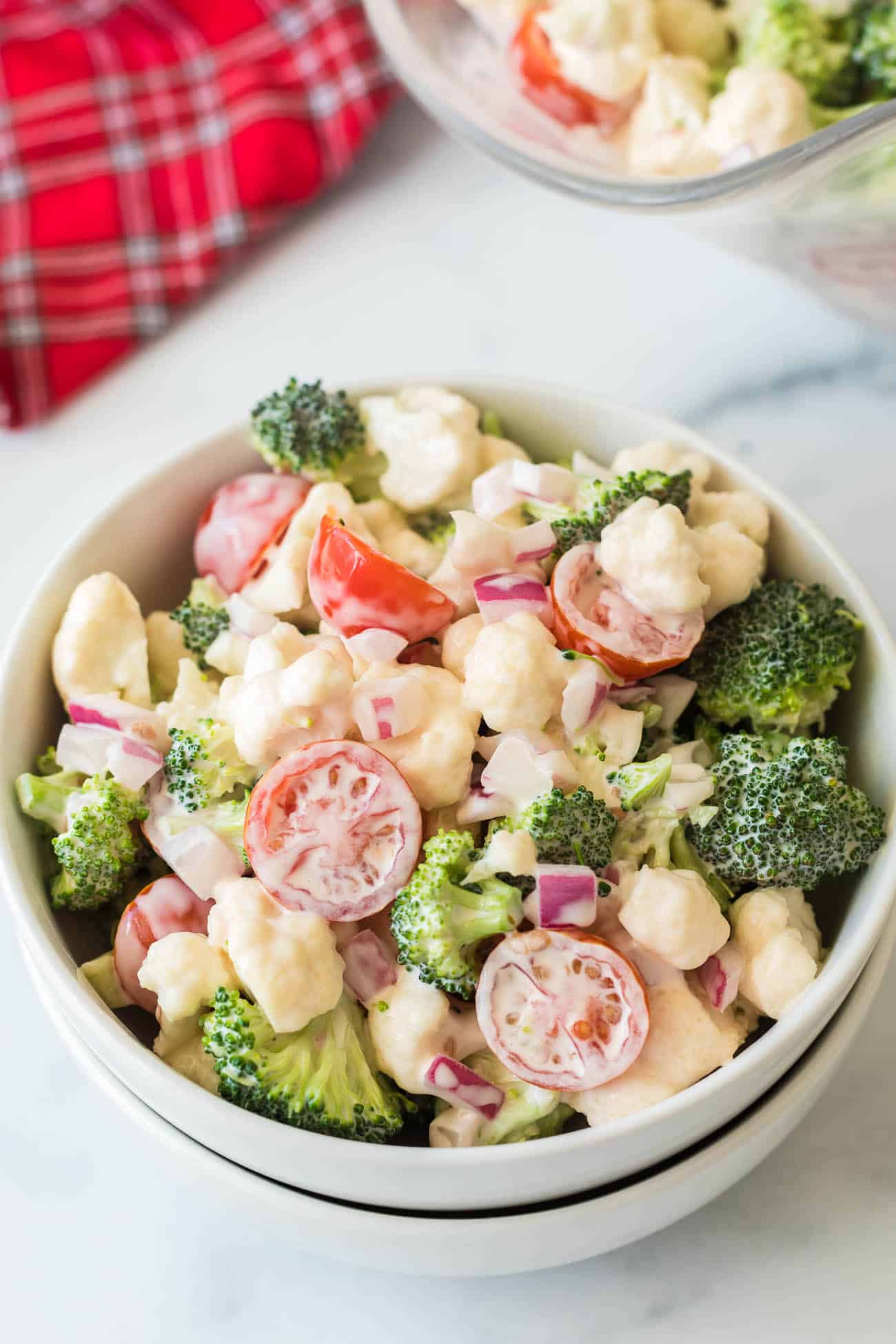 Holiday broccoli and cauliflower side dish with tomatoes in a stack of white bowls