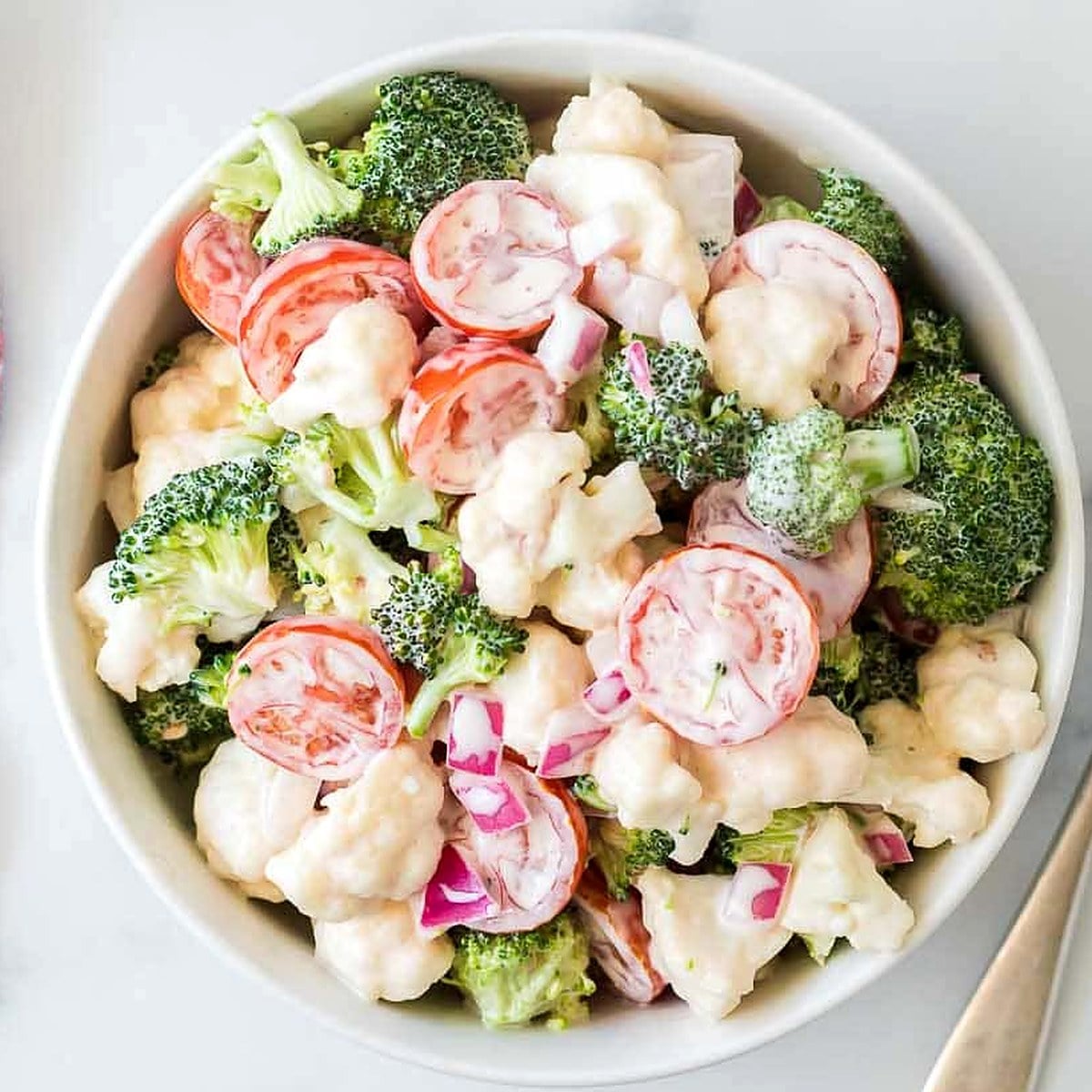Christmas Salad with broccoli, cauliflower, cherry tomatoes and red onion in a white bowl
