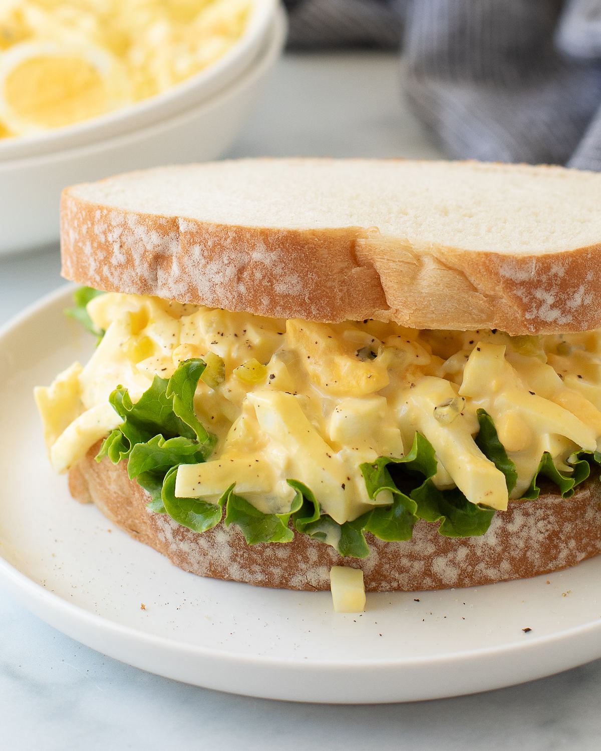 Sandwich on soft white bread with green leaf lettuce and a creamy, chunky filling.
