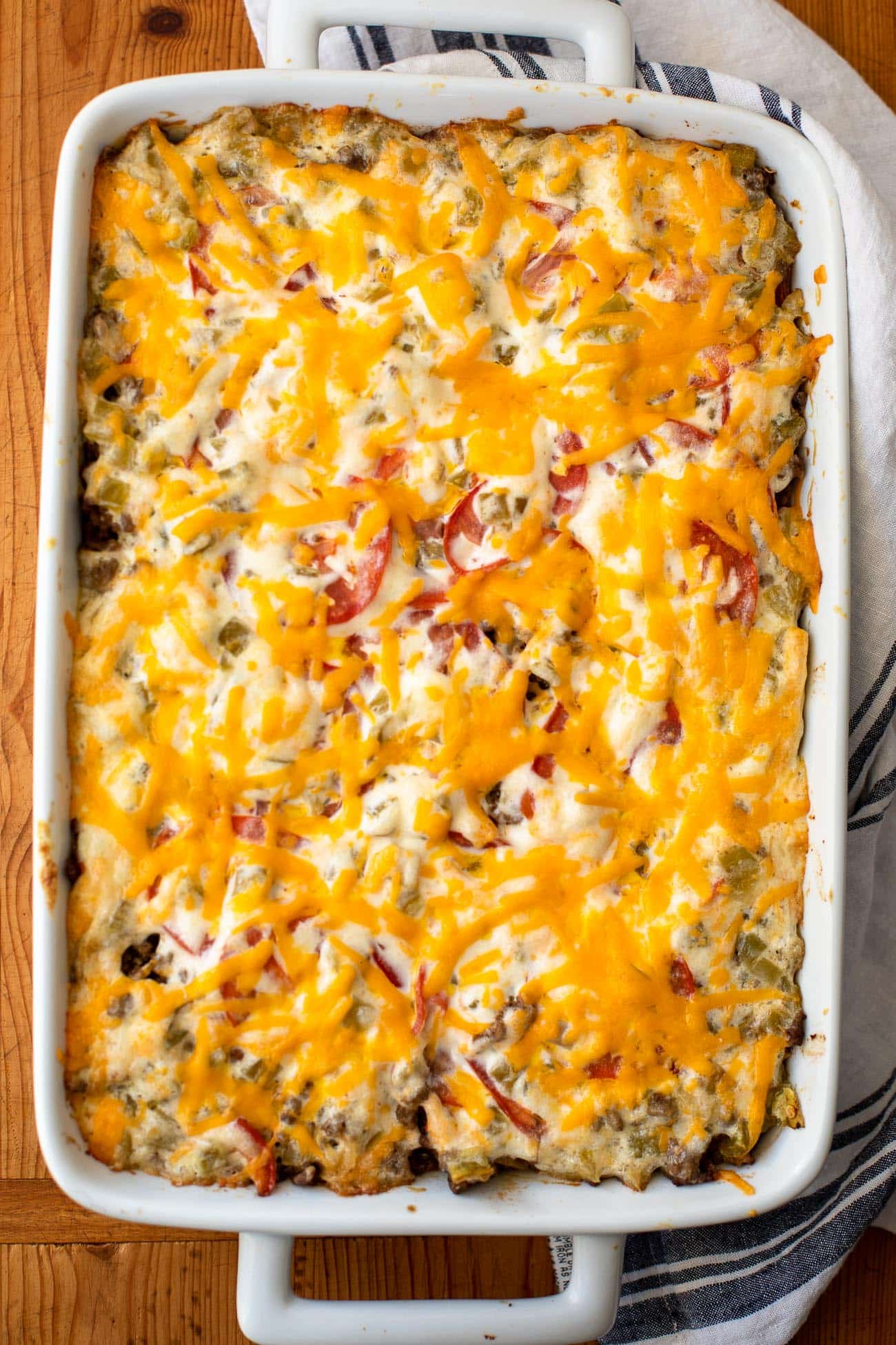 Baked layered beef dinner in a white 9x13 dish with melted cheddar on top