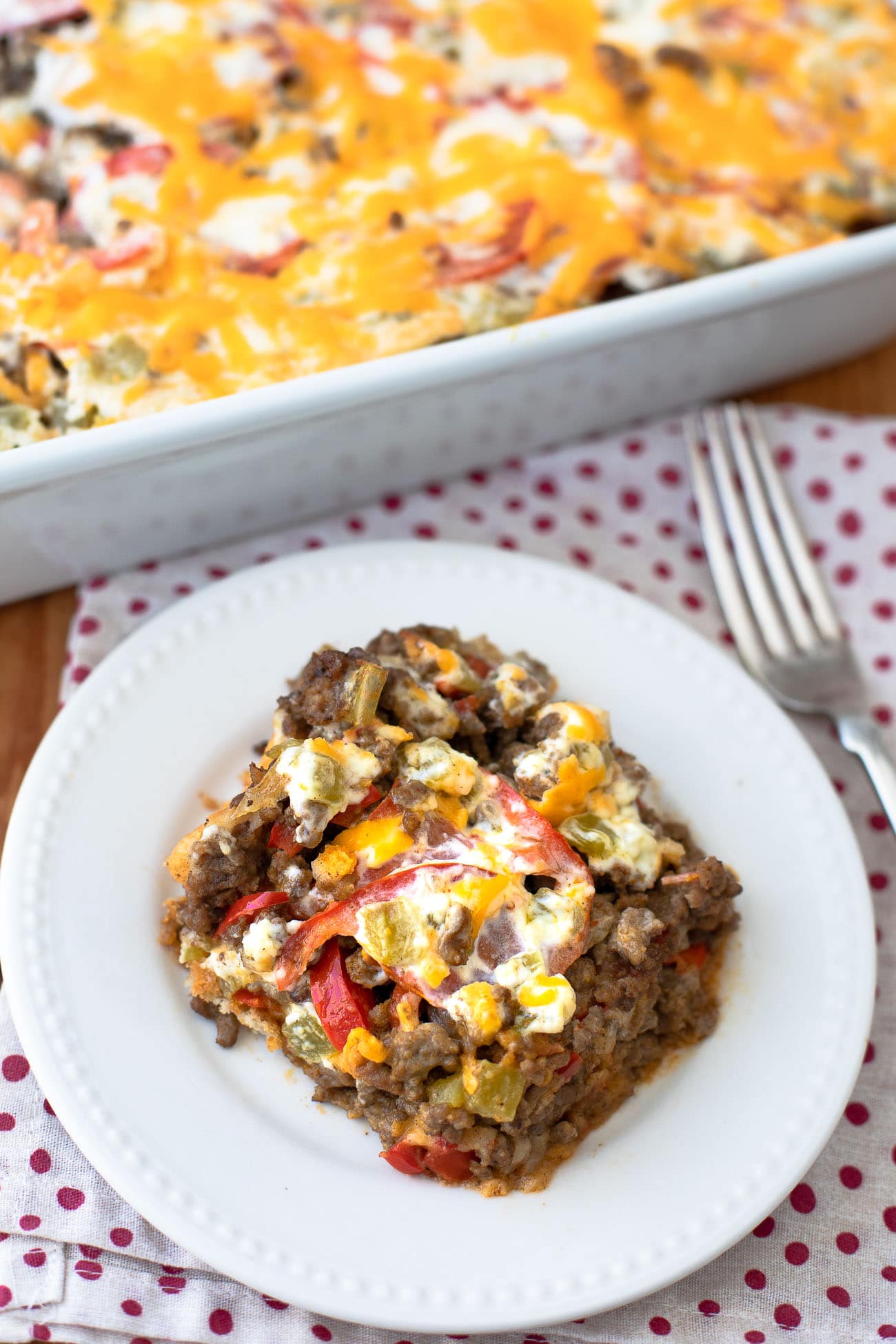 A cheesy serving with a biscuit crust on a white plate with a fork