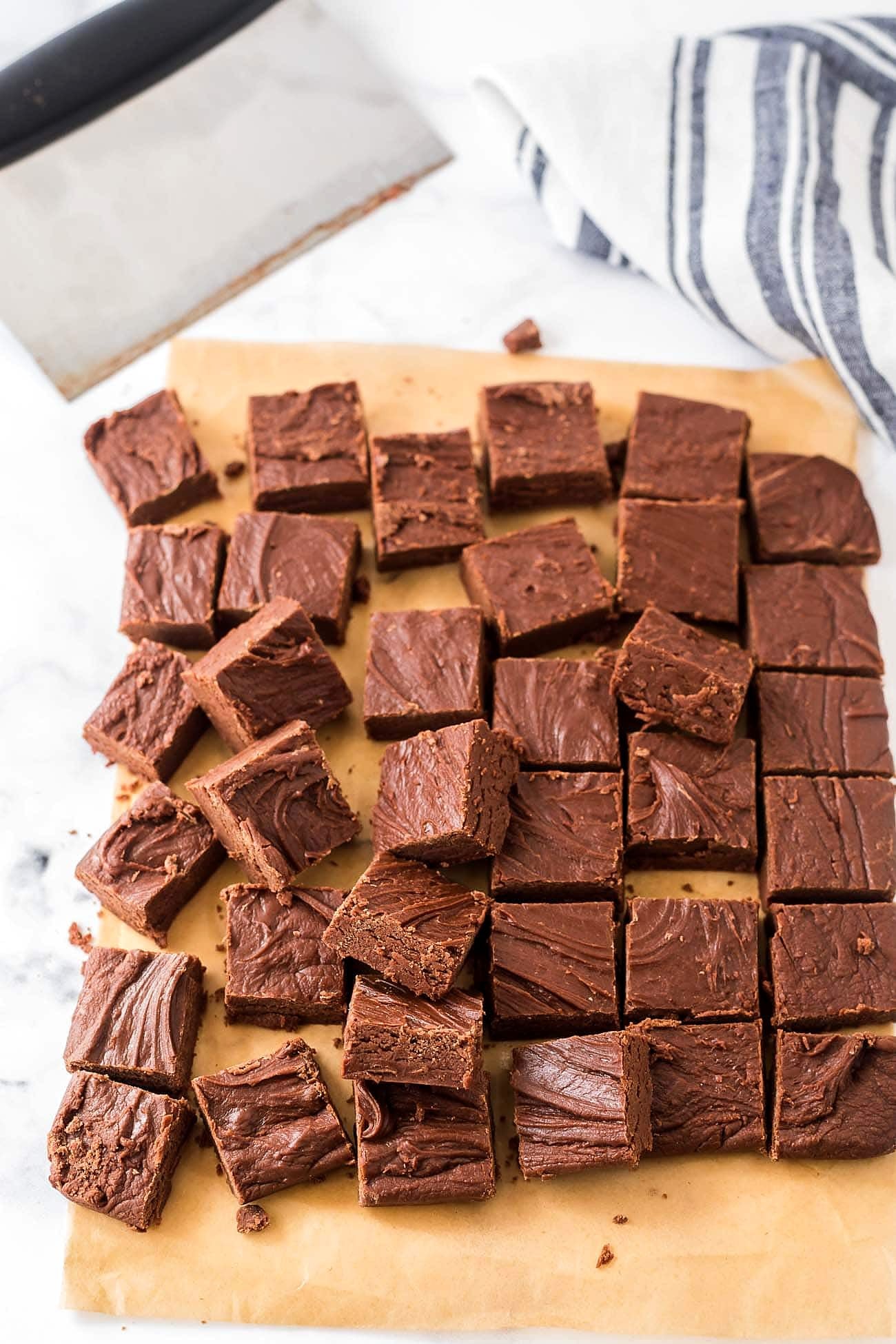 A pan of fudge cut into small squares on parchment paper