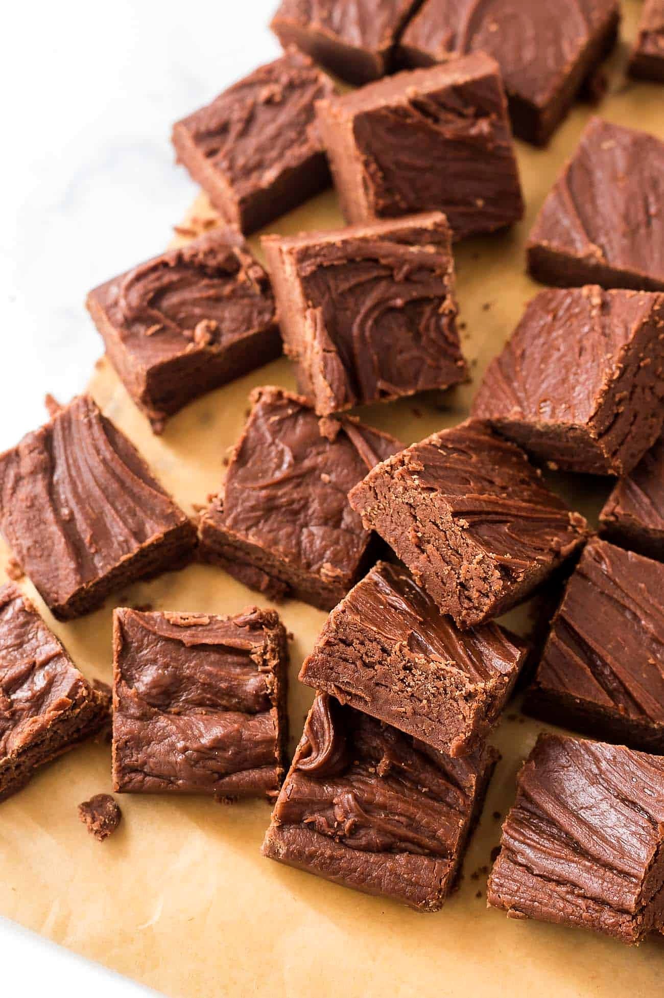 Soft chocolate fudge squares scattered on parchment paper
