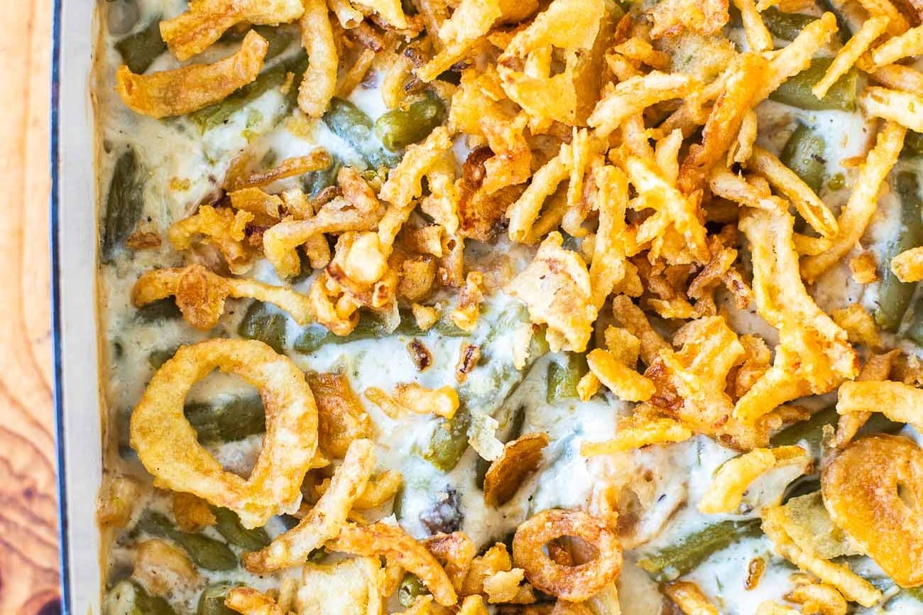Overhead view of green bean casserole in a blue baking dish, topped with golden crispy fried onions