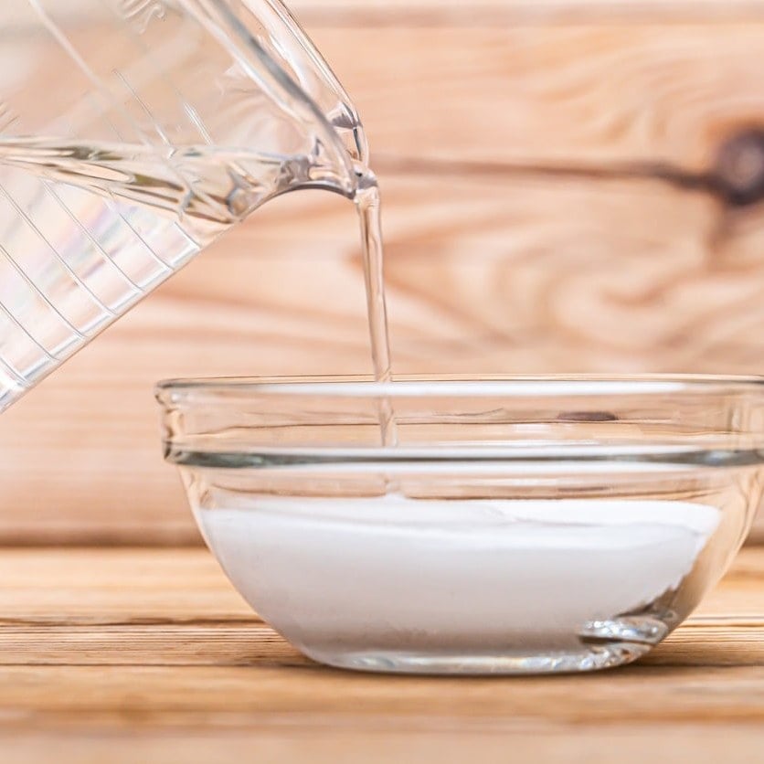 Water pouring from a measuring cup into a glass bowl