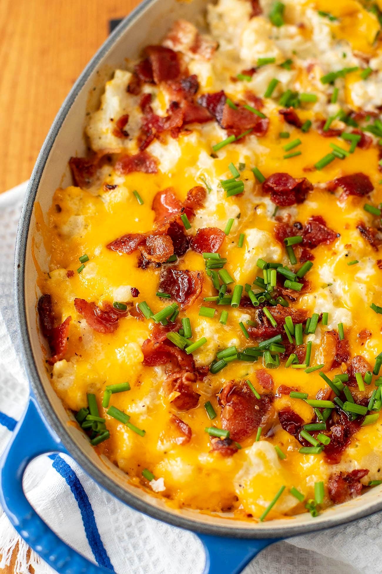 Overhead view of a cheesy cauliflower casserole with bacon and fresh chives.
