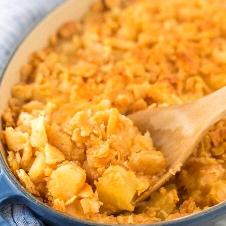 Pineapple casserole with a golden Ritz cracker topping and a wooden spoon