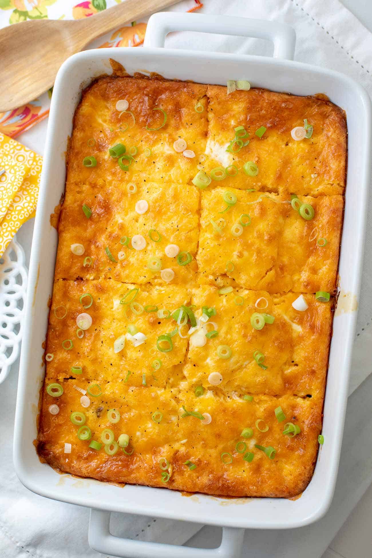 Baked sausage breakfast casserole in a white 9x13 dish topped with sliced green onions