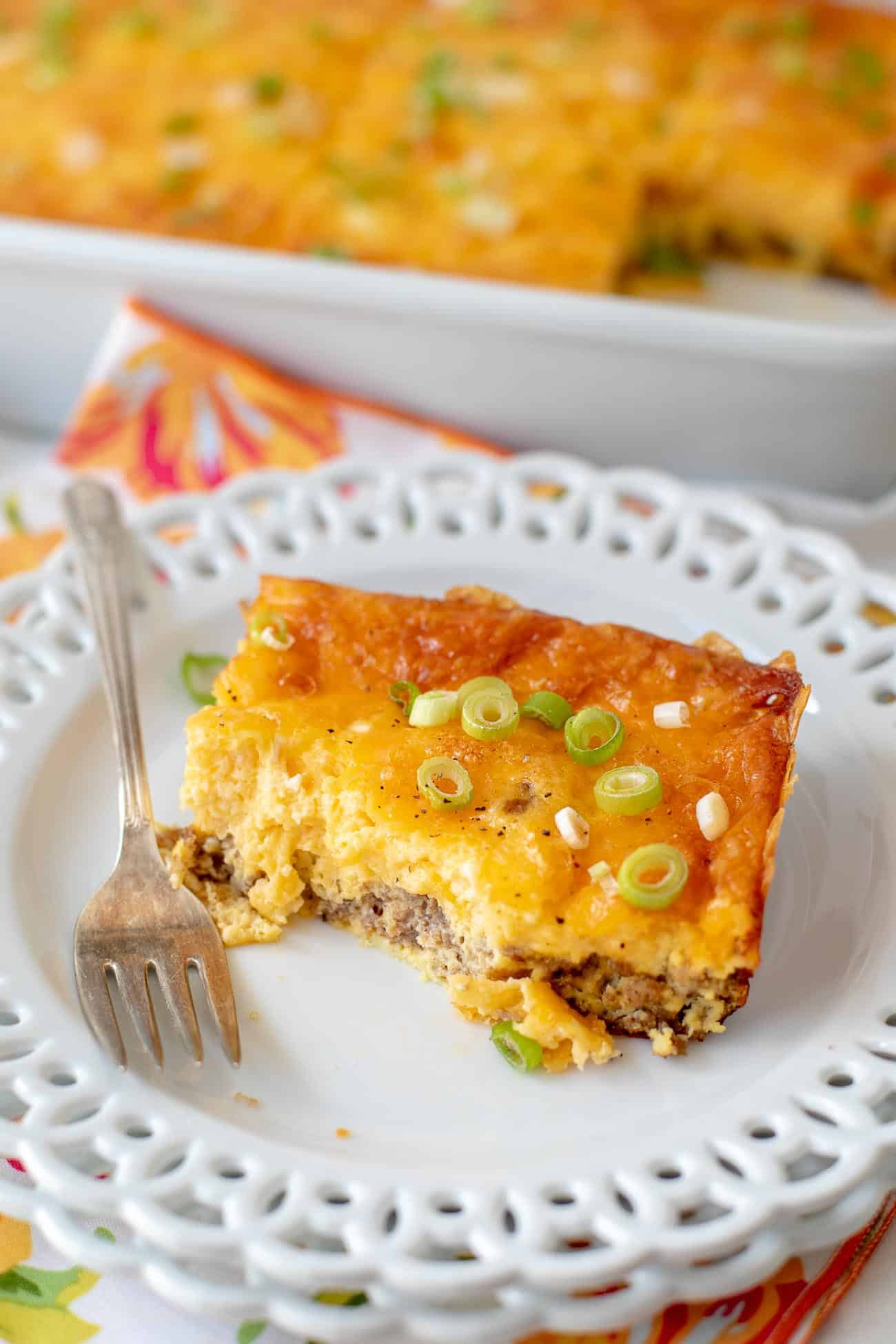 Plated square of sausage, egg and cheddar casserole with a bite taken out