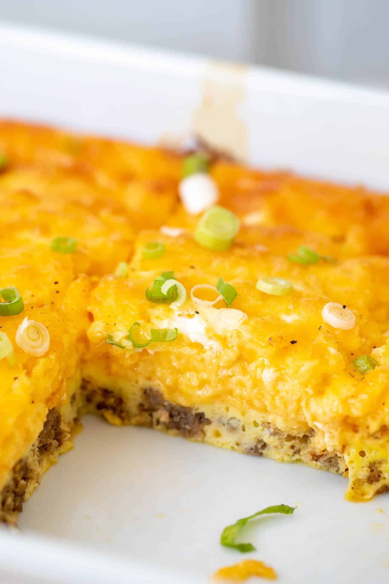 Close-up of a cut casserole square showing the sausage layer under fluffy eggs and cheese