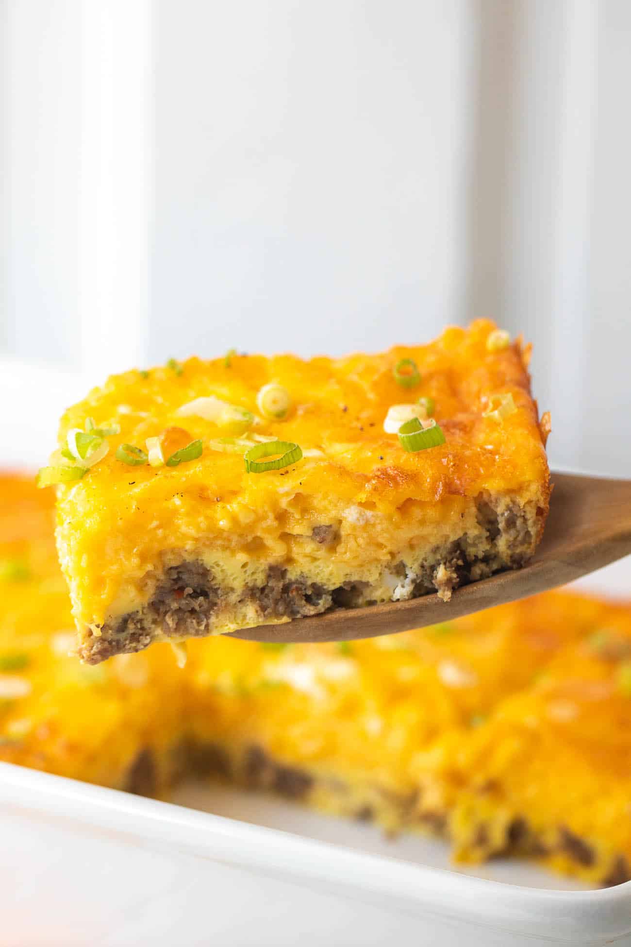Spatula lifting a cheesy square out of the baking dish