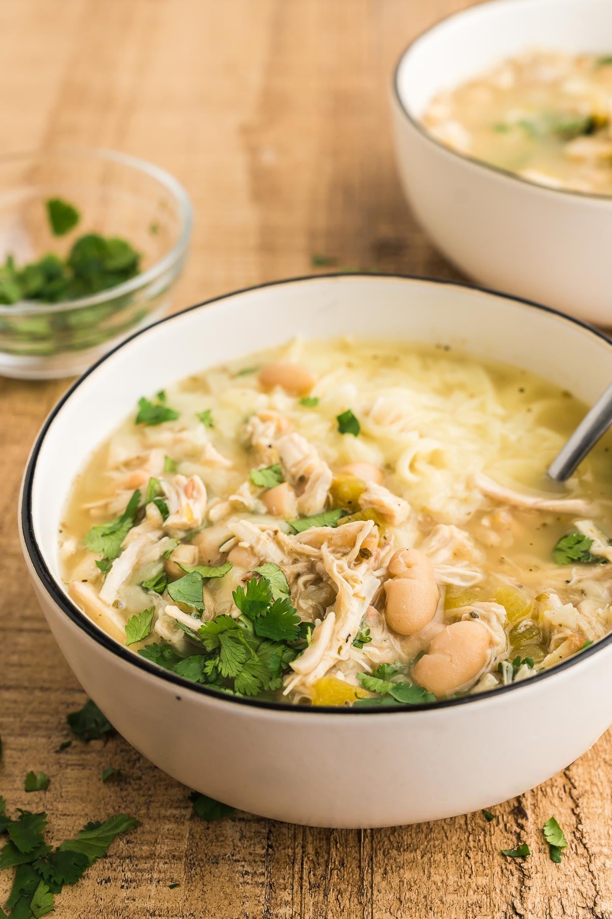 Bowl of creamy white bean chicken chili topped with melted cheese and fresh cilantro